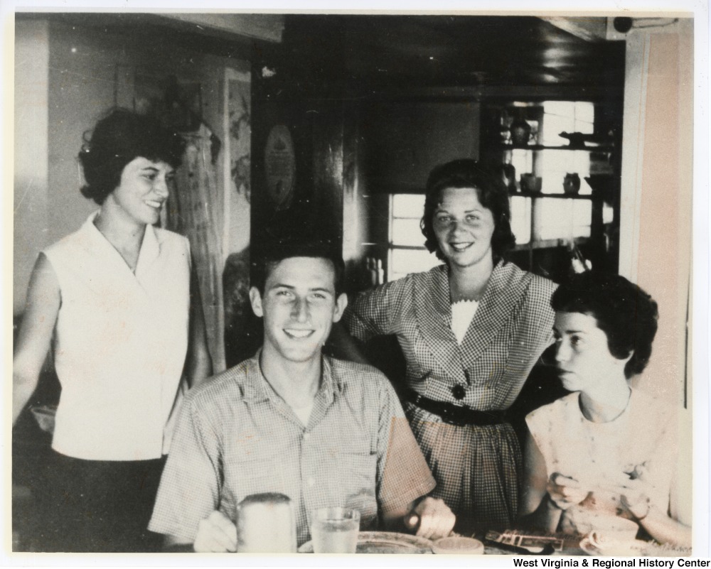 ["Jay Rockefeller seated at a table surrounded by three unidentified women."]%